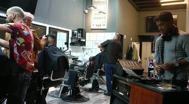 Barberos trabajando en la sala llena
