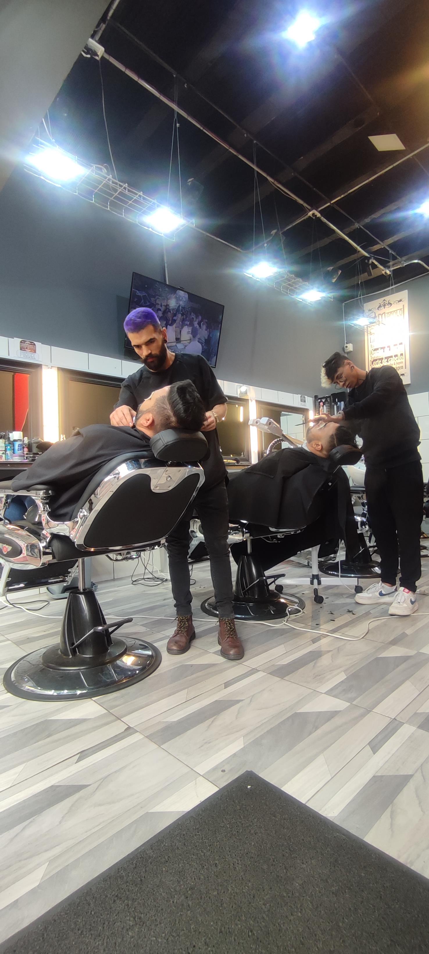 Dos barberos de Don Manolo arreglando barbas en sillas cromadas
